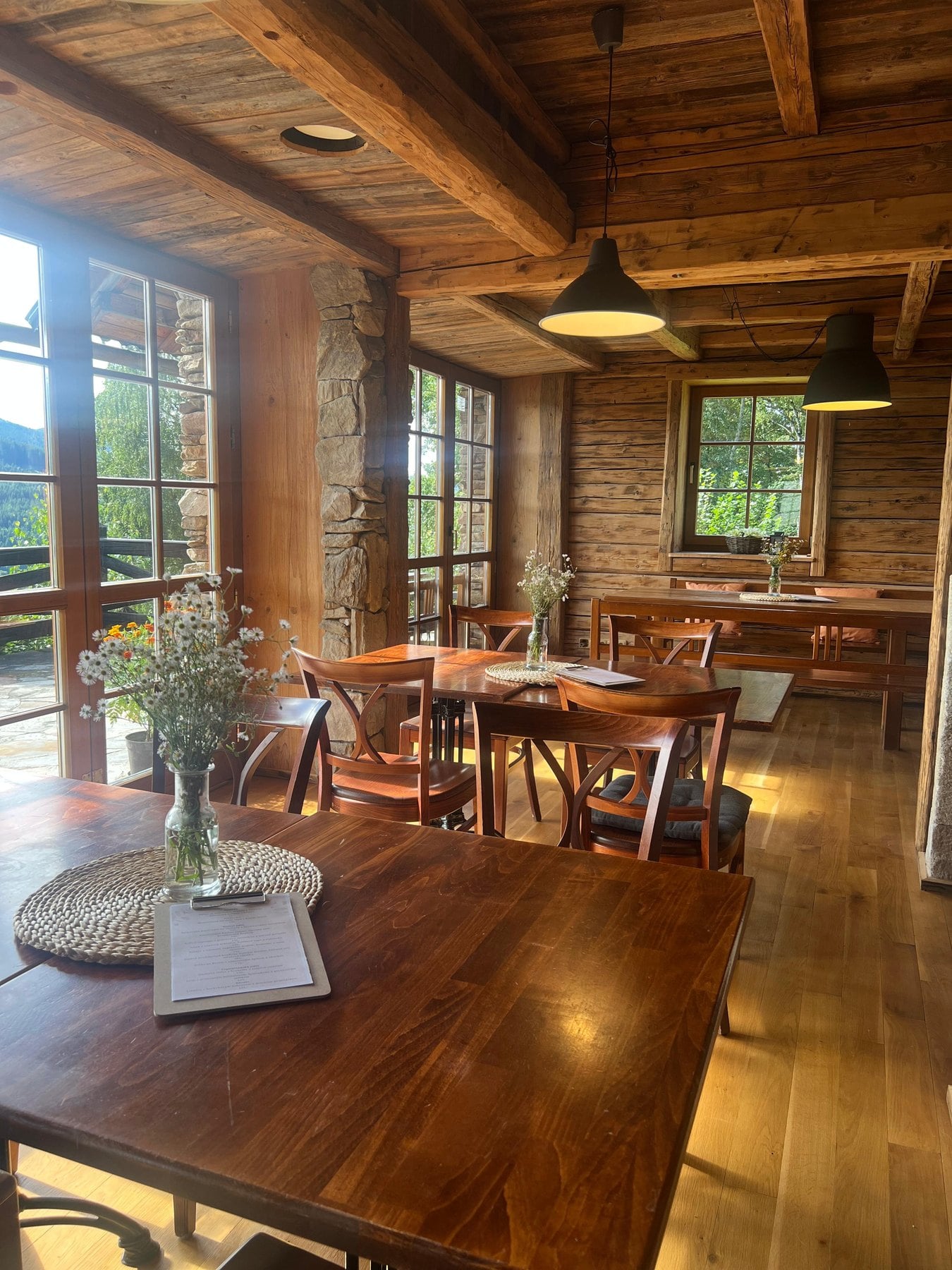 Dřevěný interiér restaurace s trámovým stropem a okny do hor